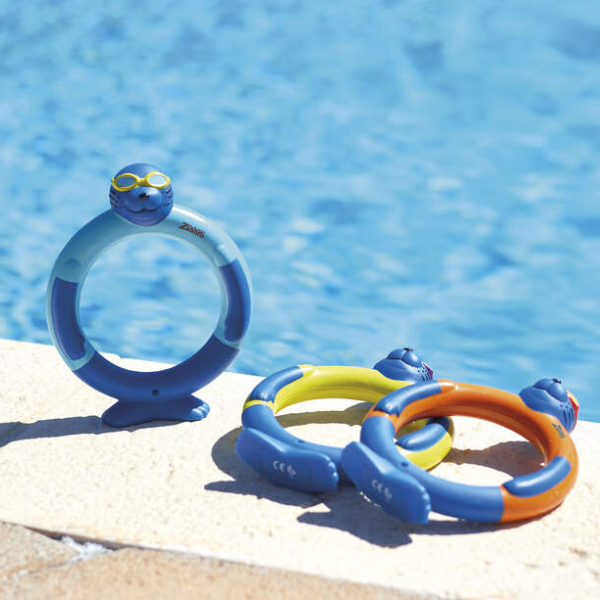 Colorful inflatable pool toys on a stone ledge with a pool