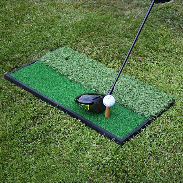 Golf practice mat with golf club and ball on grass