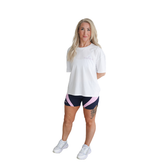 Woman wearing a white t-shirt and navy and pink Hapola shorts