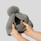 The Magni-Strip® Bobble Hat Grey held by hands against a light gray background