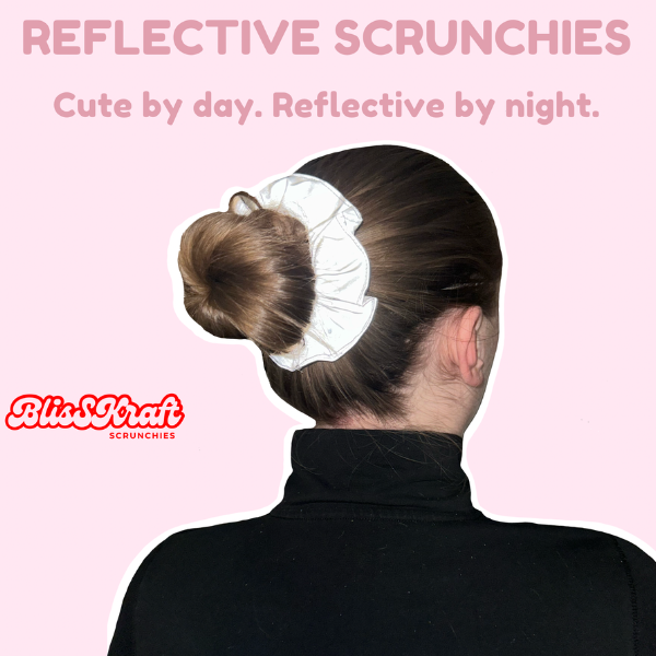 Girl with her hair in a bun using a reflective scrunchie.  There is a caption saying 'Reflective Scrunchies' and then 'Cute by day. Reflective by night.' The BlisSKraft logo is also on there. 