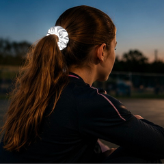 Dark evening with a long-haired young girl looking into the distance wearing a reflective scunchie.