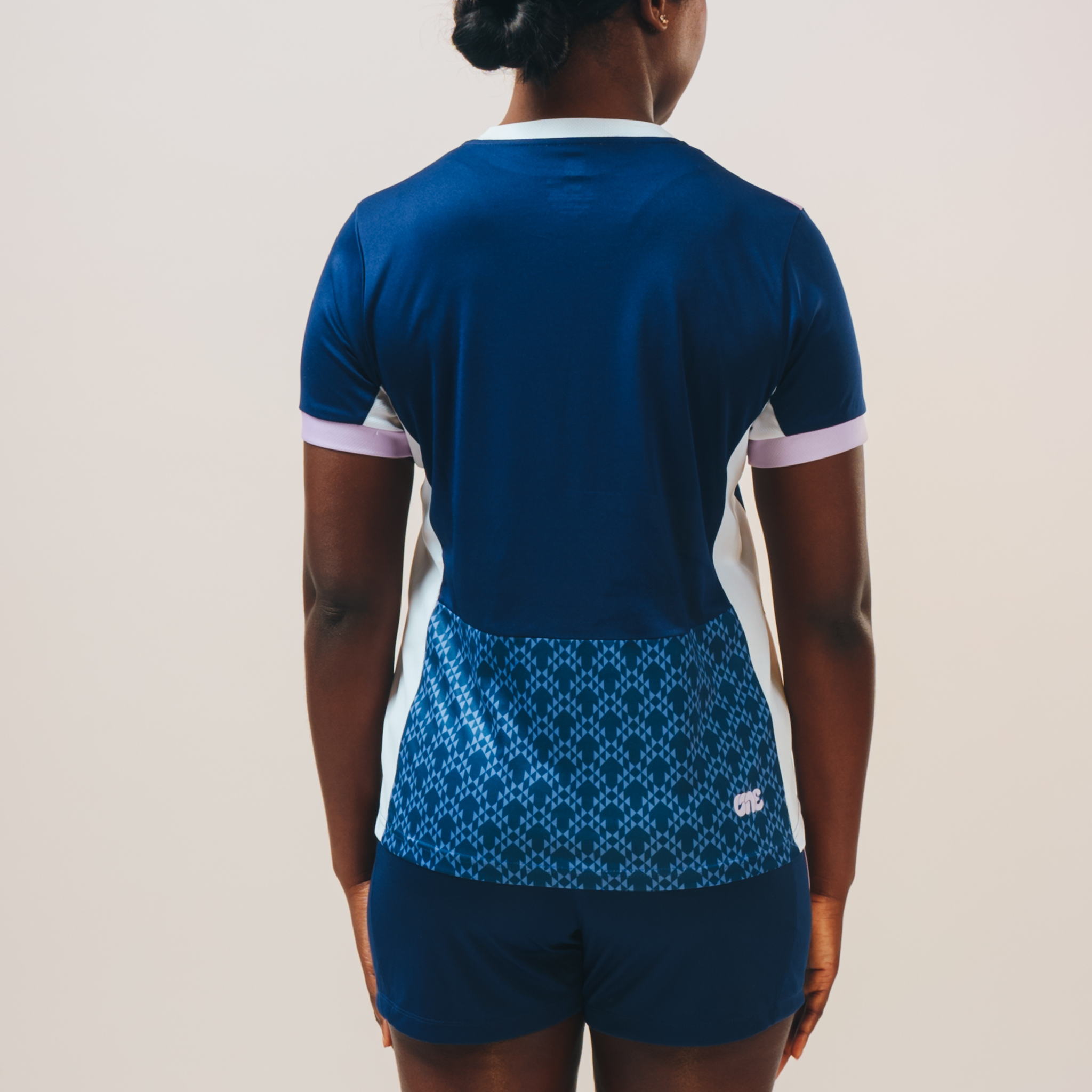 Girl with her back to the camera wearing the Eleven as One blue training top, showing the pattern on the back at the bottom. 