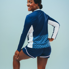 The behind view of long sleeve training top in blue with white panels and a patterned panel on the back with different shades of blue.  The training shorts are visible too with white traim.  