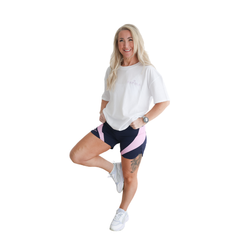 Woman wearing a white t-shirt and navy and pink Hapola shorts on a white background