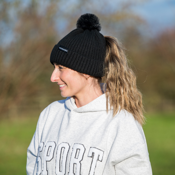 The Magni-Strip® Bobble Hat Black worn by woman outdoors
