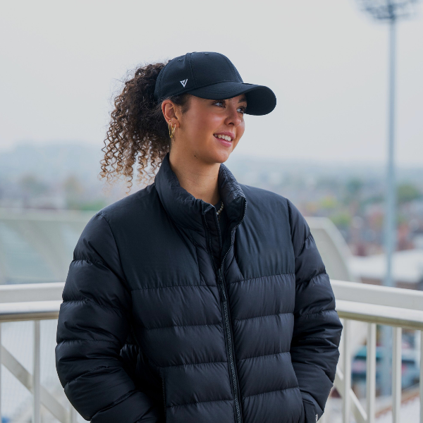 Woman wearing a black puffer jacket and Magni-Strip® Lifestyle Cap Black outdoors